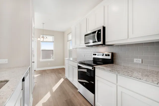 a kitchen with stainless steel appliances granite countertop white cabinets granite counter tops and a hard wood floors