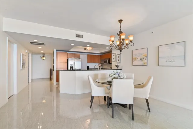 a dining room with wooden floor a chandelier a wooden table and chairs