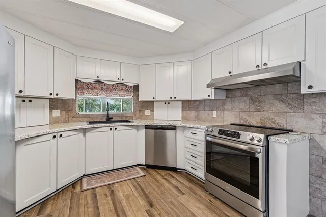 a kitchen with granite countertop a stove top oven sink and cabinets