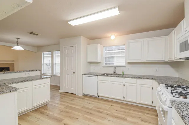 a kitchen with granite countertop a sink stove and cabinets