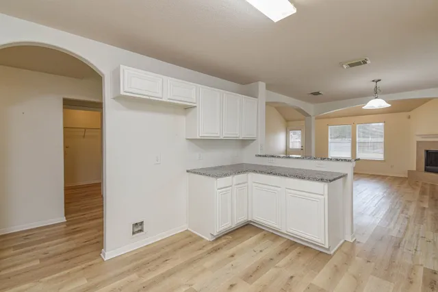 a kitchen with granite countertop white cabinets and wooden floor
