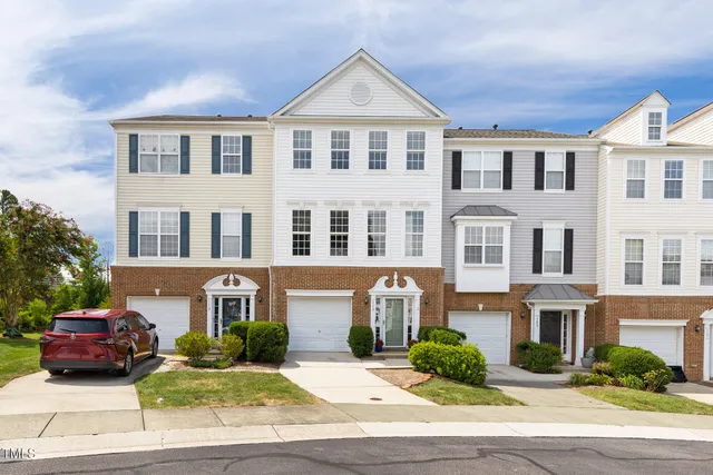 a front view of a residential apartment building with yard and parking