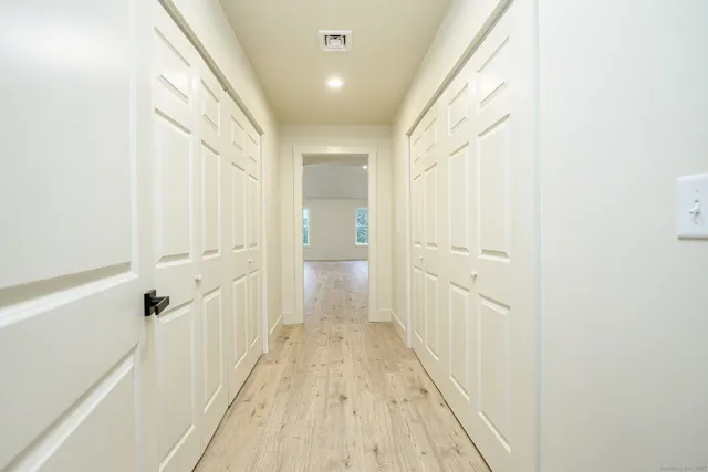 a view of a hallway with wooden floor and a bathroom