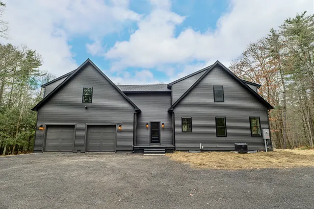 a front view of house with yard and trees in the background