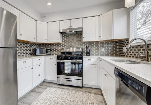 a kitchen with white cabinets and appliances