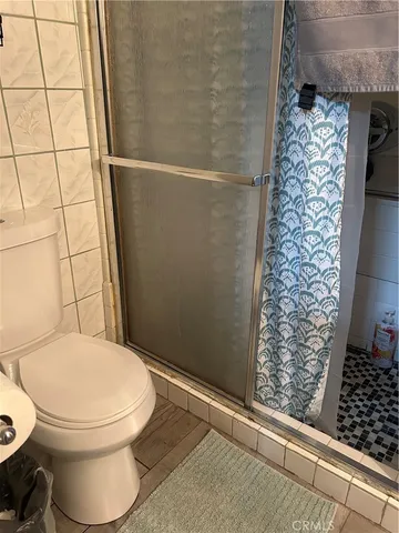 a bedroom with a bed a dresser and wooden floor