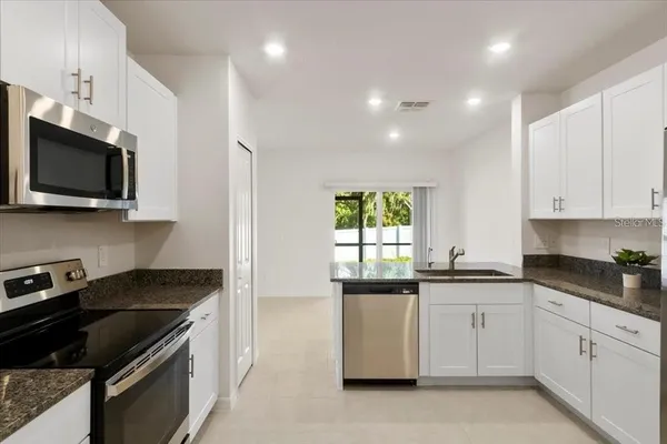 a kitchen with white cabinets a sink stove and microwave