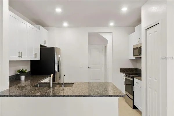 a kitchen with stainless steel appliances granite countertop a sink refrigerator and cabinets