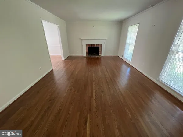 wooden floor fireplace and windows in an empty room