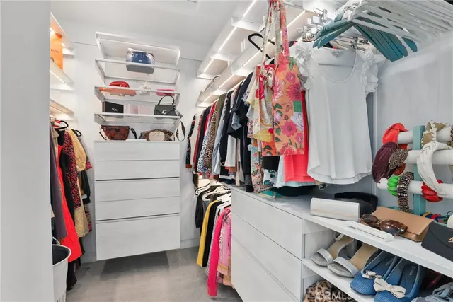a view of walk in closet with clothes and shoes