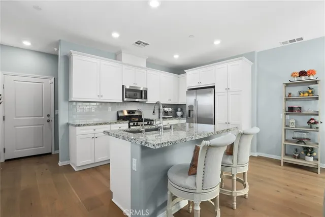 a kitchen with stainless steel appliances granite countertop a stove a sink a refrigerator a microwave oven with a dining table and chairs