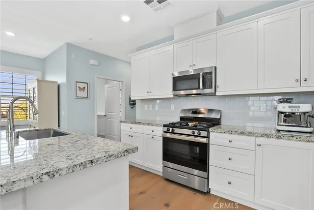 a kitchen with granite countertop a stove sink and microwave