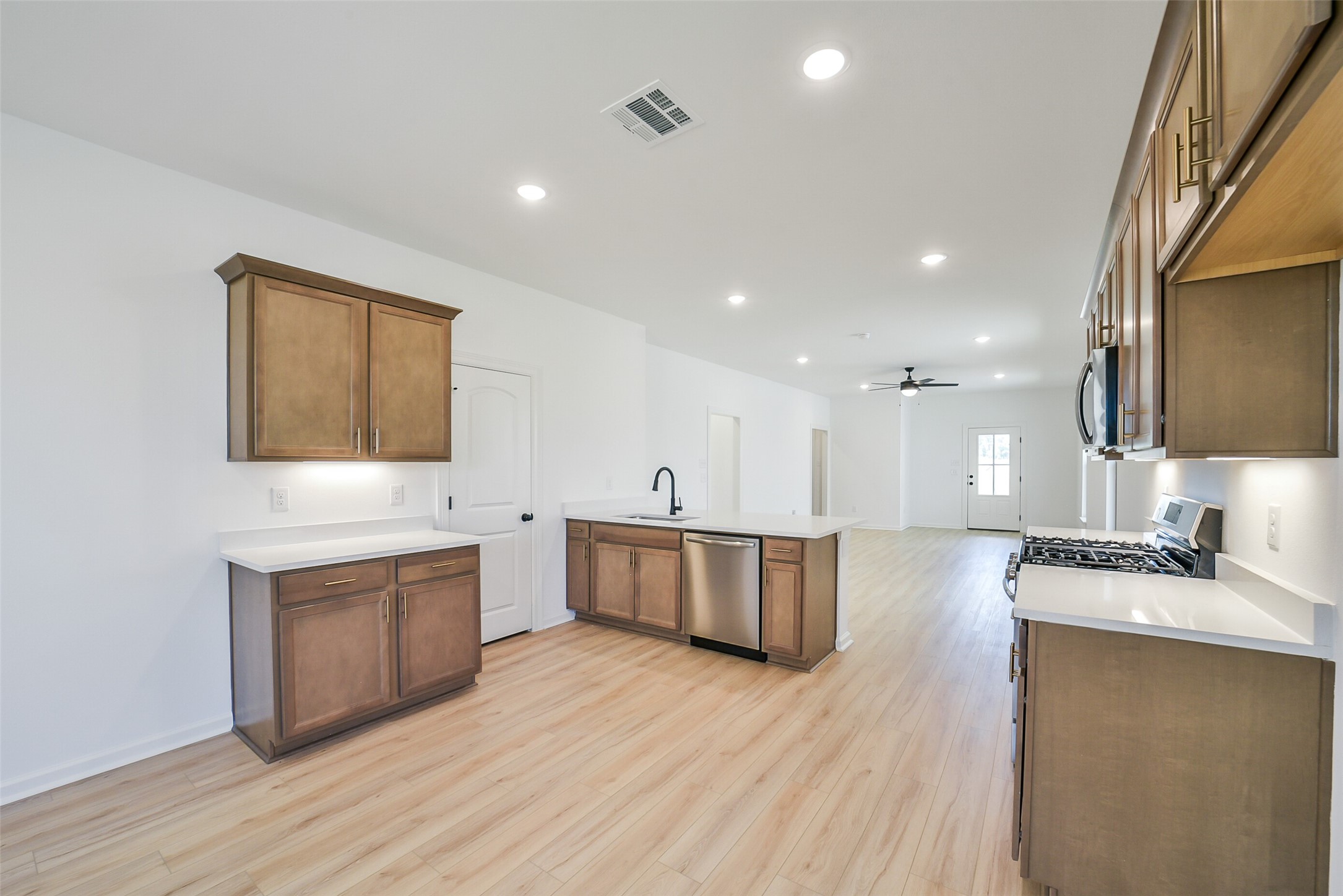 40708 Pessi Road Magnolia, TX 77354 - Photo 10 of 30 a large kitchen with stainless steel appliances a large counter top a stove a sink and a wooden floors
