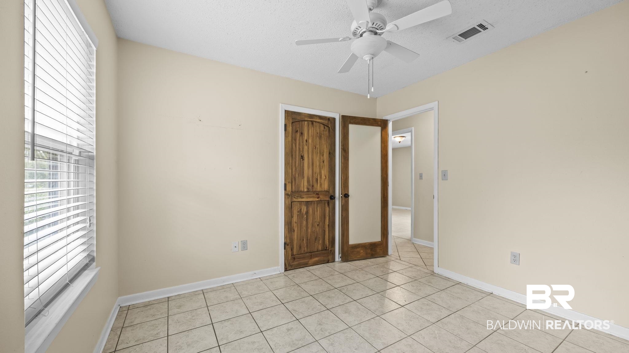 15096 Highland Circle Foley, AL 36535 - Photo 25 of 52 Room featuring ceramic tile flooring, a window with horizontal blinds, a ceiling fan with integrated lighting, and two wood-paneled doors