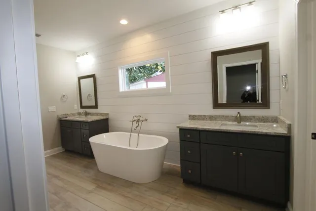 a spacious bathroom with a double vanity sink mirror and bathtub
