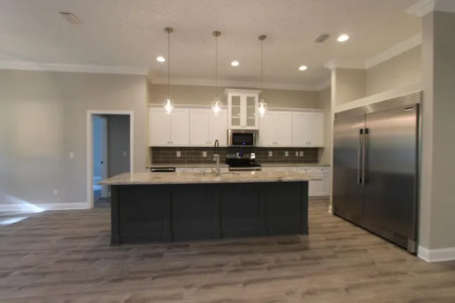 a view of kitchen with granite countertop a sink and cabinets