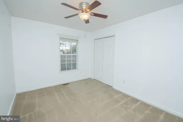 an empty room with a window and a fan