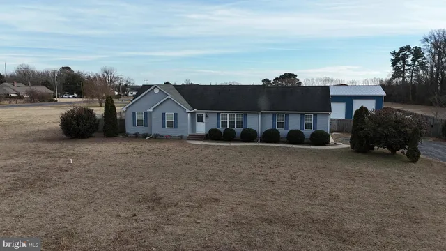 a view of house with a big yard and large trees