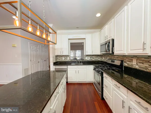 a kitchen with stainless steel appliances granite countertop a stove a sink and white cabinets