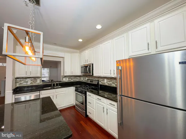 a kitchen with granite countertop a refrigerator stove top oven and sink