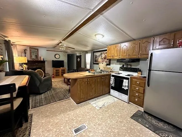 a kitchen with stainless steel appliances kitchen island granite countertop a refrigerator a stove top oven a sink dishwasher and white cabinets with wooden floor