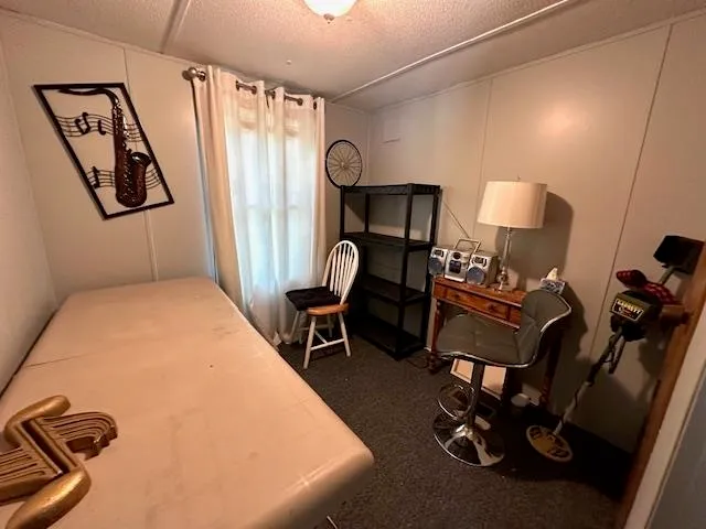 a bedroom with a bed a desk and chair with the wooden floor