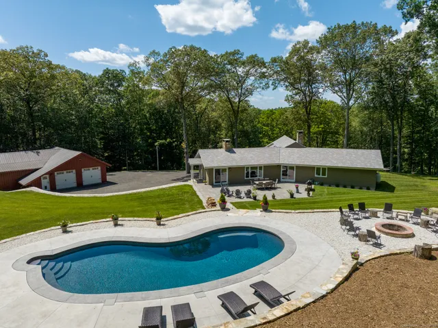 a view of a swimming pool with lawn chairs under an umbrella