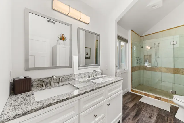 a bathroom with a granite countertop sink a mirror and a shower
