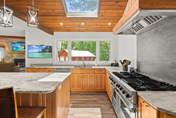 a kitchen with stainless steel appliances granite countertop a stove a sink and a white wooden cabinets