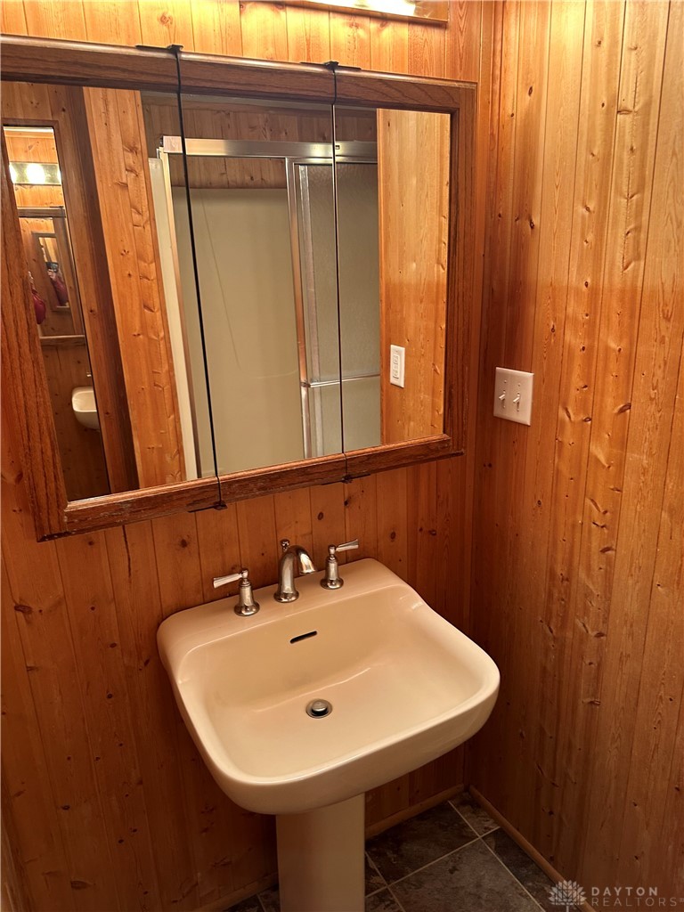 1358 Hanes Road Dayton, OH 45434 - Photo 10 of 21 This cozy bathroom features a classic pedestal sink and natural wood paneling for a rustic feel.