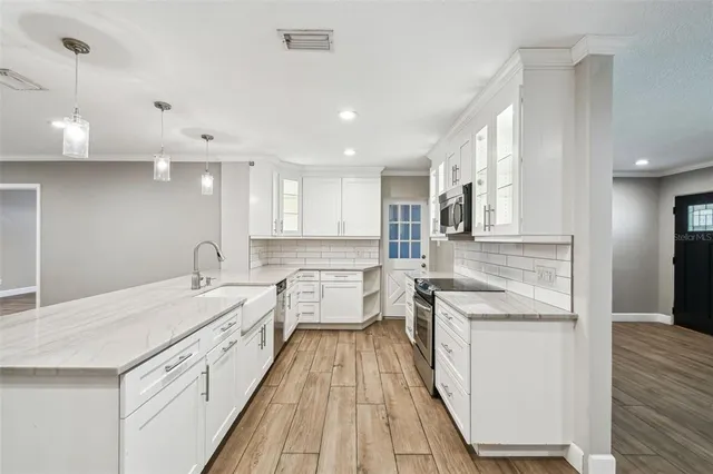 a large kitchen with kitchen island a stove a sink a center island and wooden floor