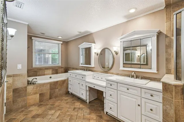 a spacious bathroom with a granite countertop double vanity sink a mirror and a bathtub