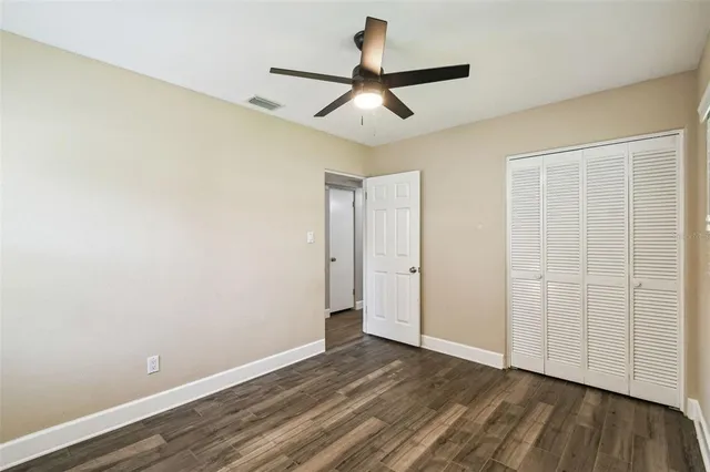 a view of a room with wooden floor and a ceiling fan