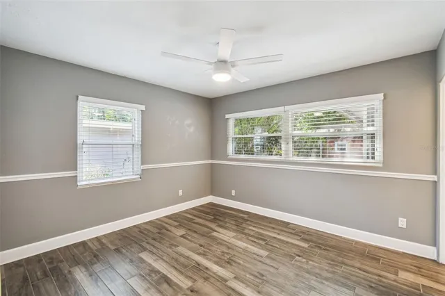 a view of empty room with wooden floor and fan
