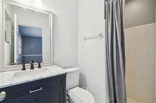 a bathroom with a granite countertop sink toilet and mirror