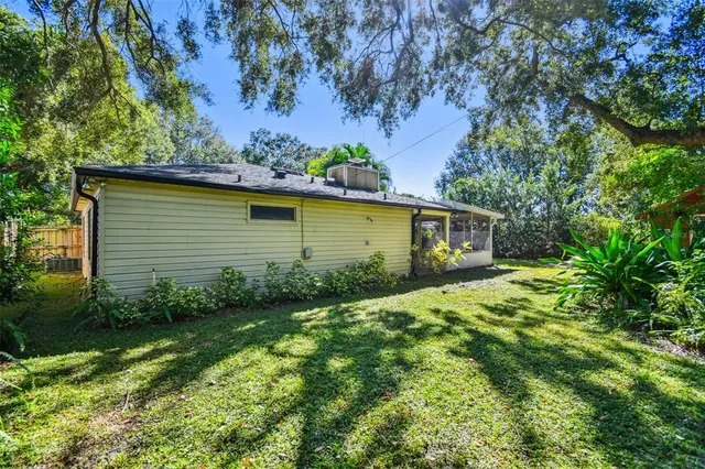 a backyard of a house with plants and large tree
