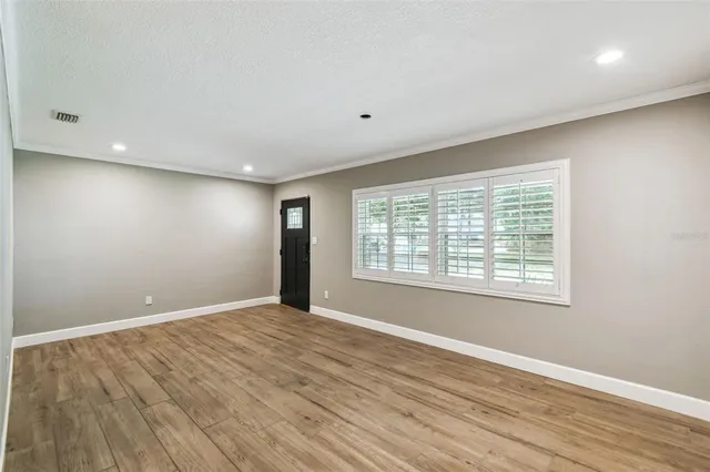 a view of an empty room with wooden floor and a window