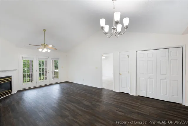 a view of an empty room with wooden floor and a chandelier