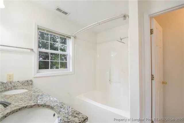 a bathroom with a granite countertop sink and a bathtub