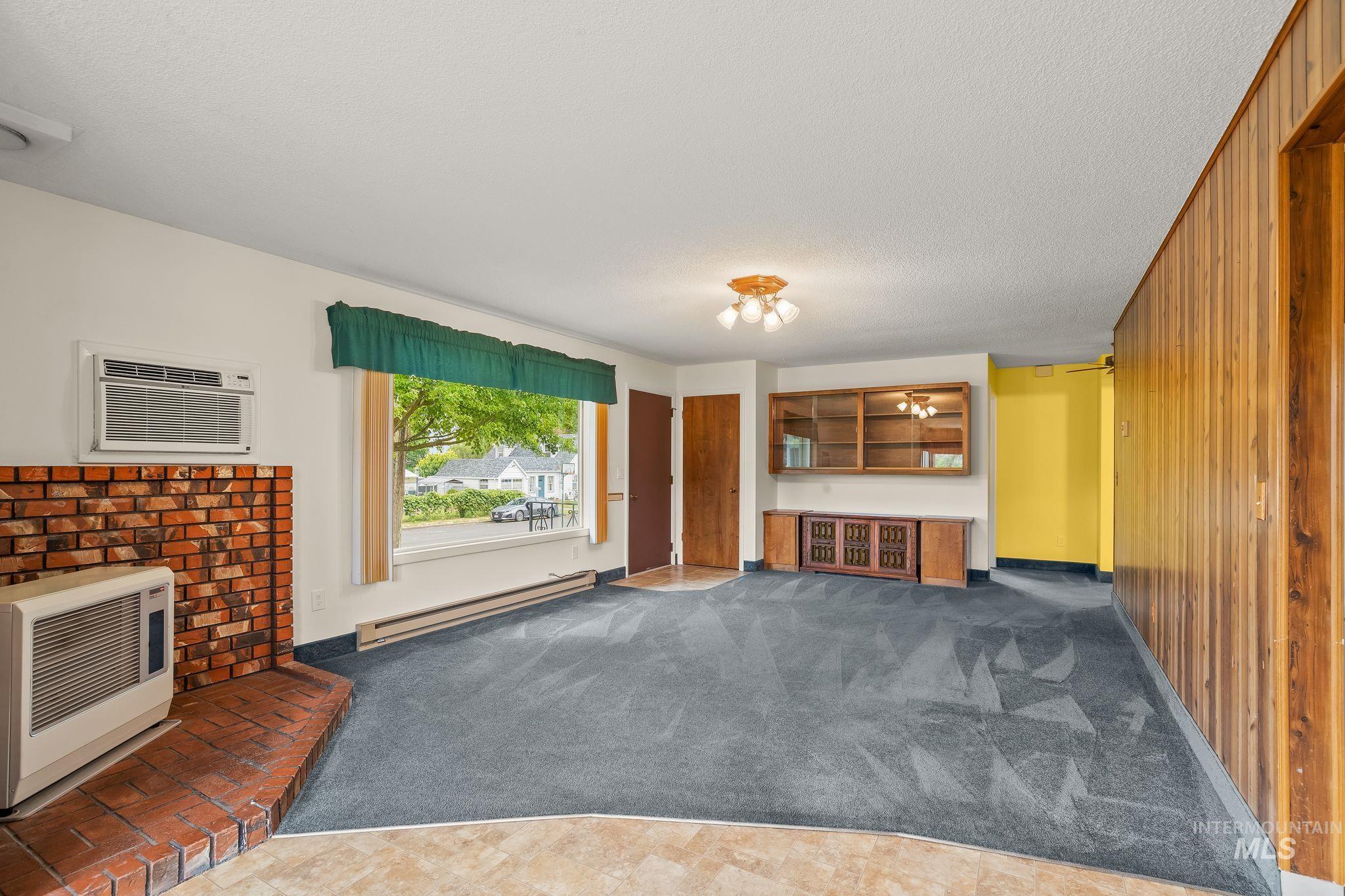 1721 3rd Street Lewiston, ID 83501 - Photo 29 of 45 Living area featuring a brick fireplace, built-in display cabinetry, wood paneling, and a large front-facing window