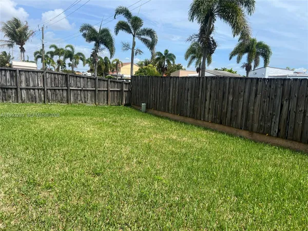 a view of a backyard with large trees and wooden fence