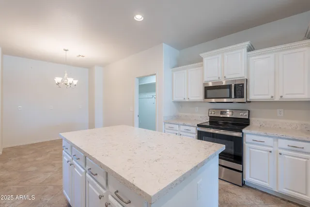 a kitchen with a stove a sink a refrigerator and white cabinets with wooden floor