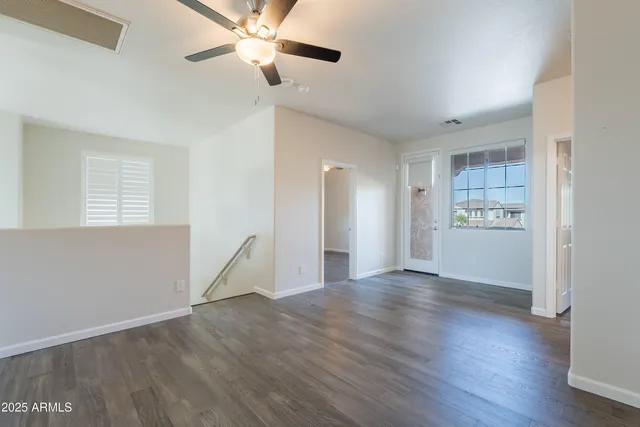 an empty room with wooden floor and ceiling fan