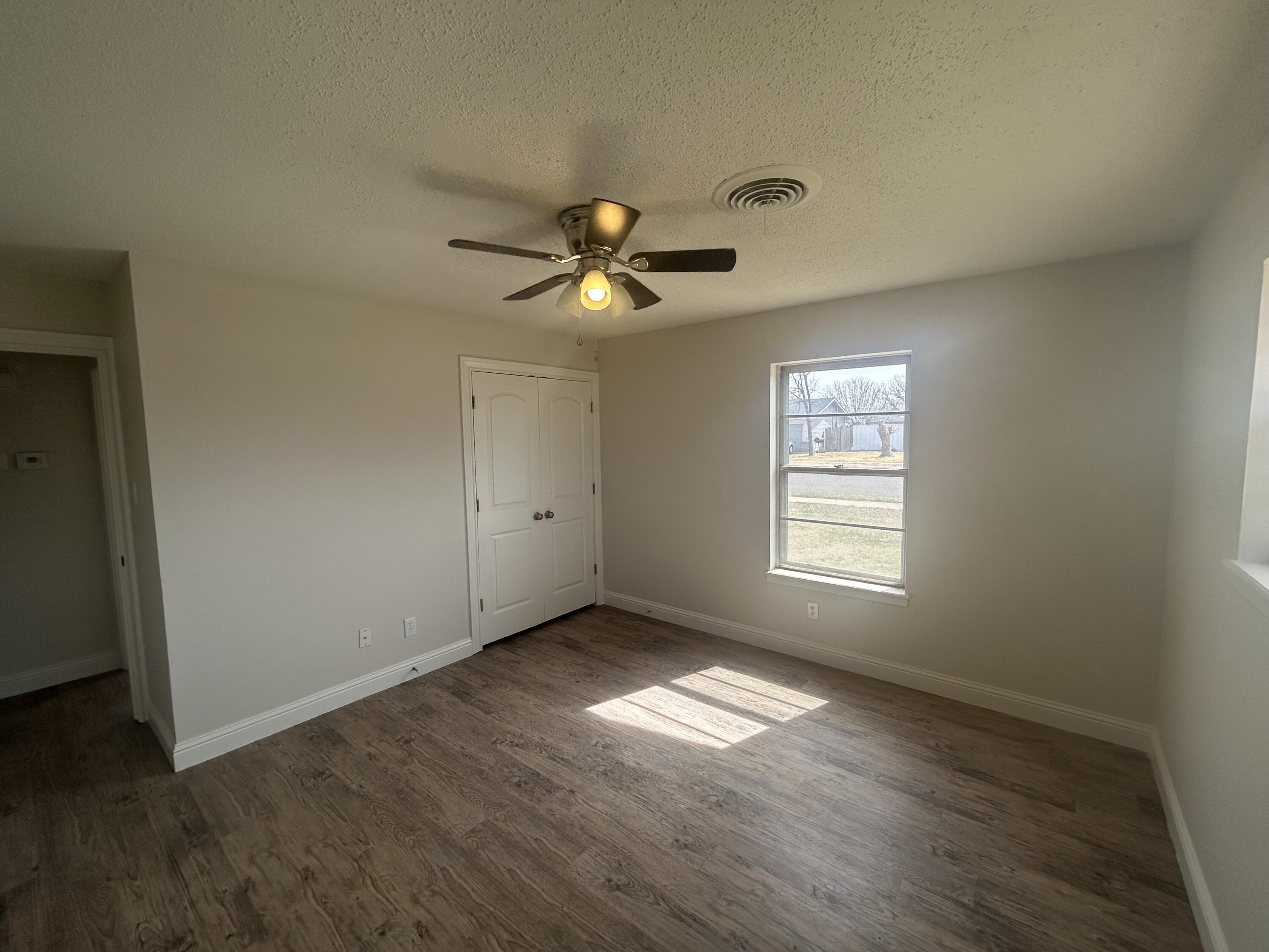 111 Bobby Street Levelland, TX 79336 - Photo 14 of 25 a view of empty room with wooden floor and fan