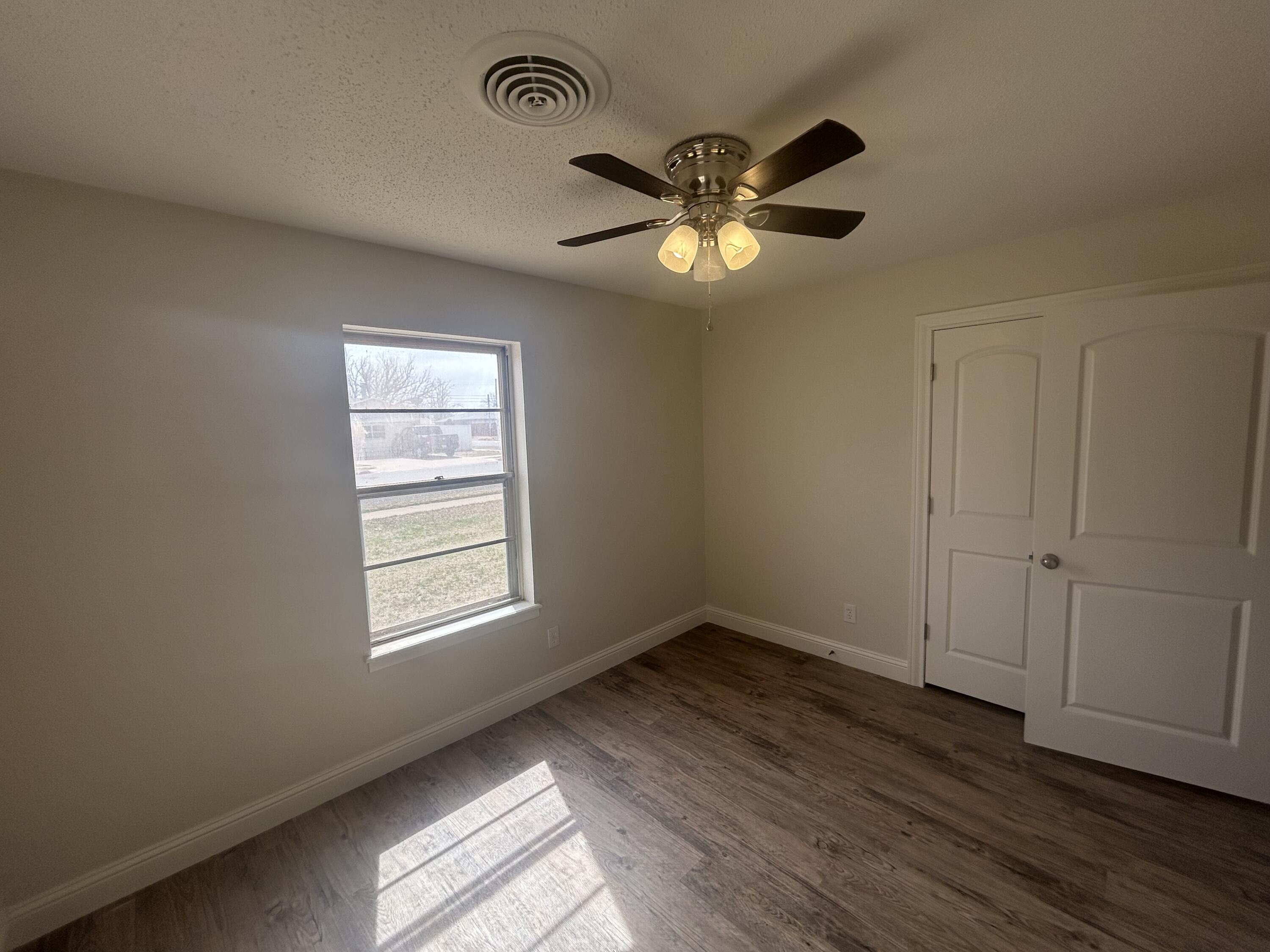 111 Bobby Street Levelland, TX 79336 - Photo 16 of 25 a view of an empty room with a window and wooden floor