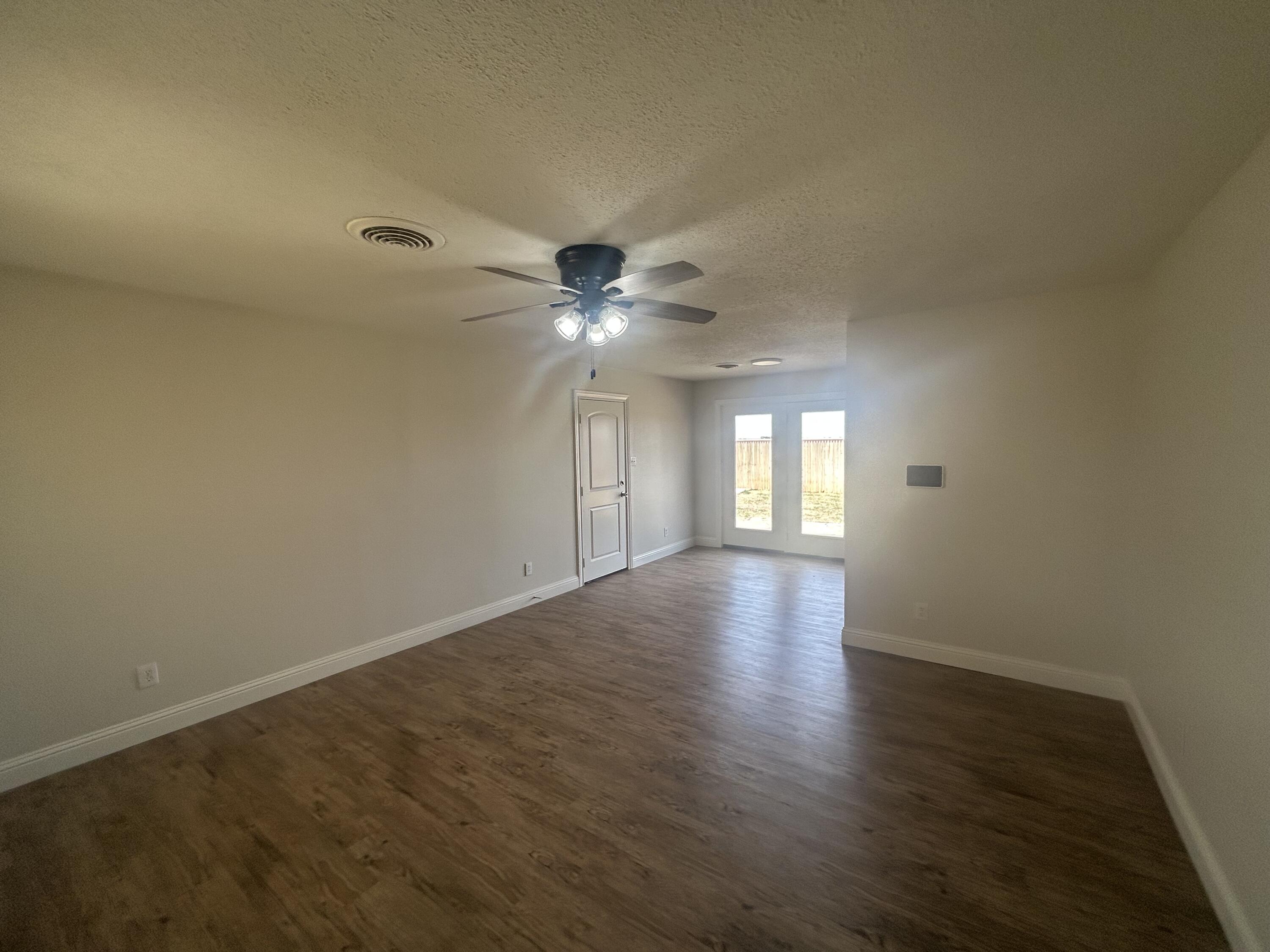 111 Bobby Street Levelland, TX 79336 - Photo 2 of 25 an empty room with wooden floor and windows