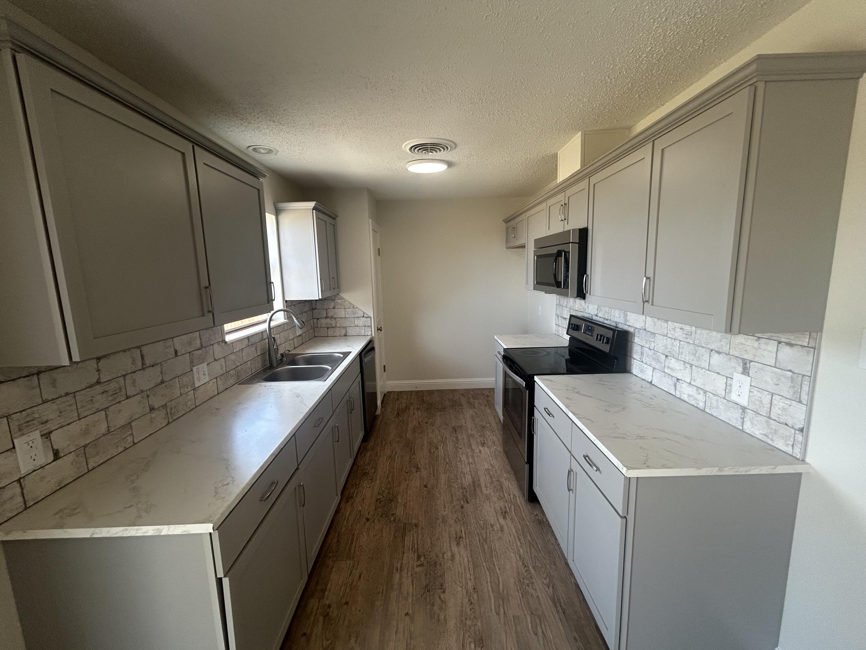 111 Bobby Street Levelland, TX 79336 - Photo 4 of 25 a kitchen with stainless steel appliances a sink a stove and a refrigerator