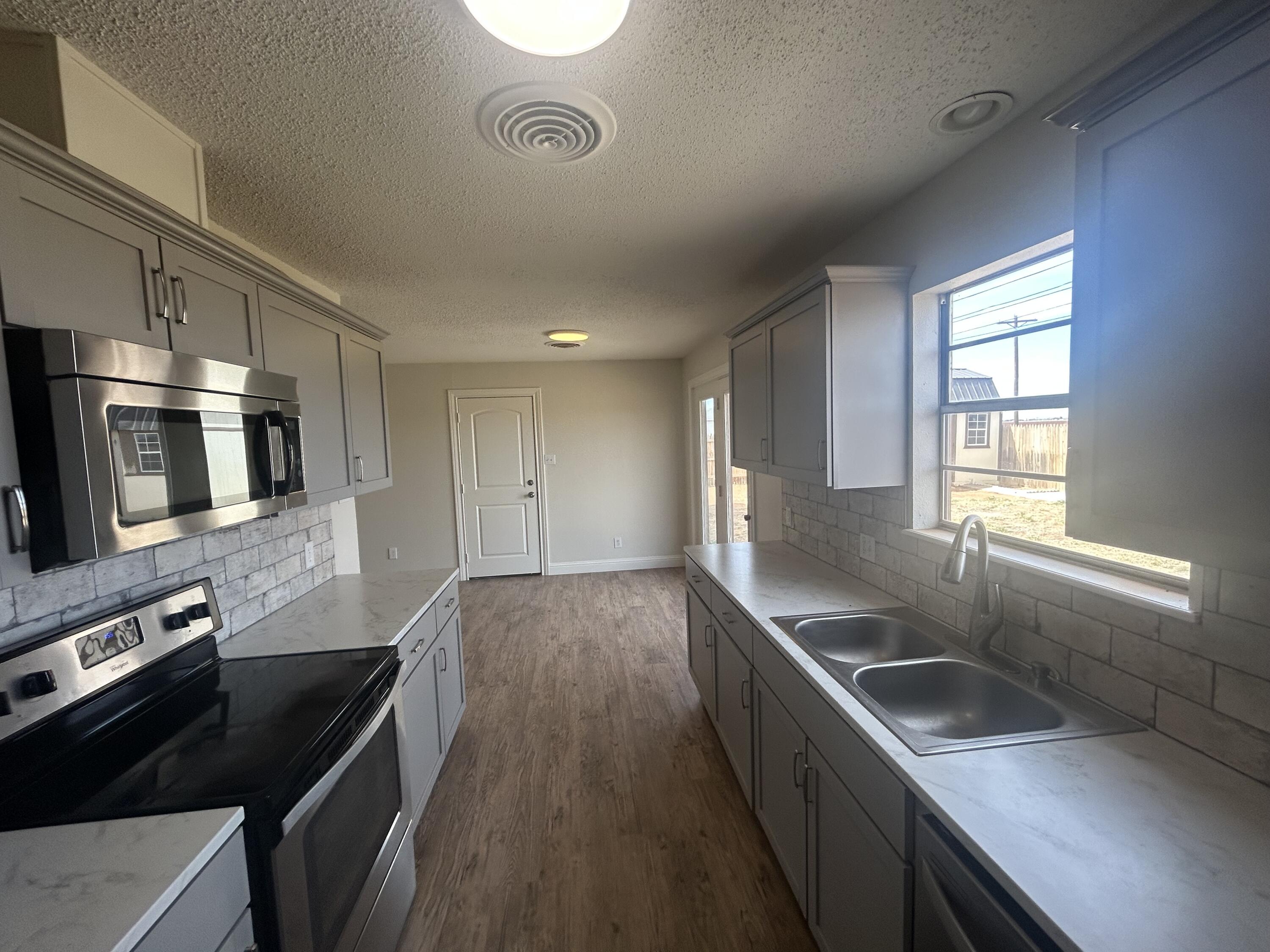 111 Bobby Street Levelland, TX 79336 - Photo 7 of 25 a kitchen with stainless steel appliances granite countertop a sink stove and refrigerator