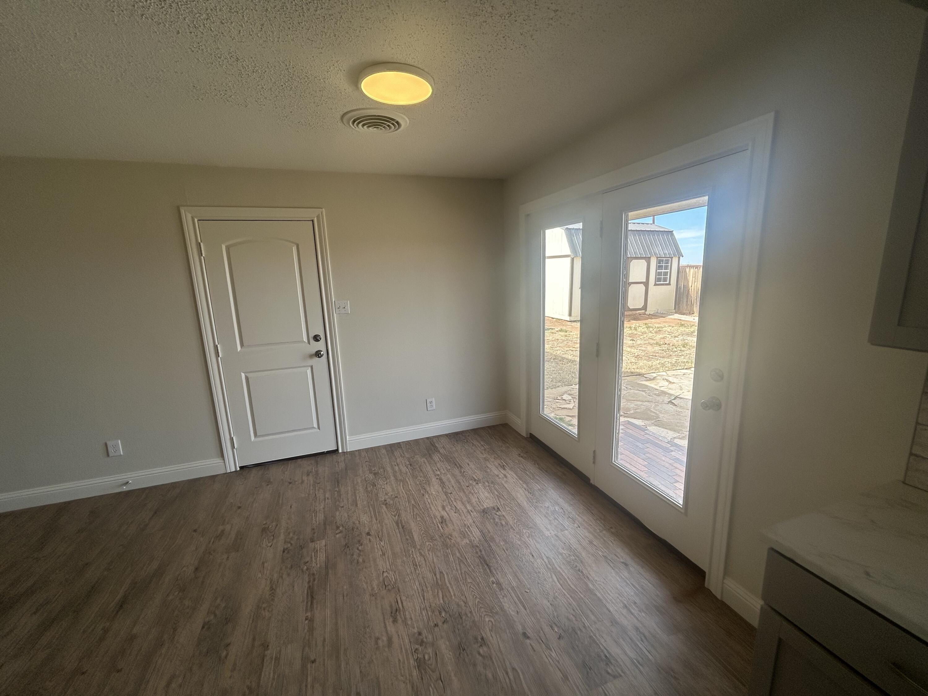 111 Bobby Street Levelland, TX 79336 - Photo 8 of 25 an empty room with wooden floor and windows