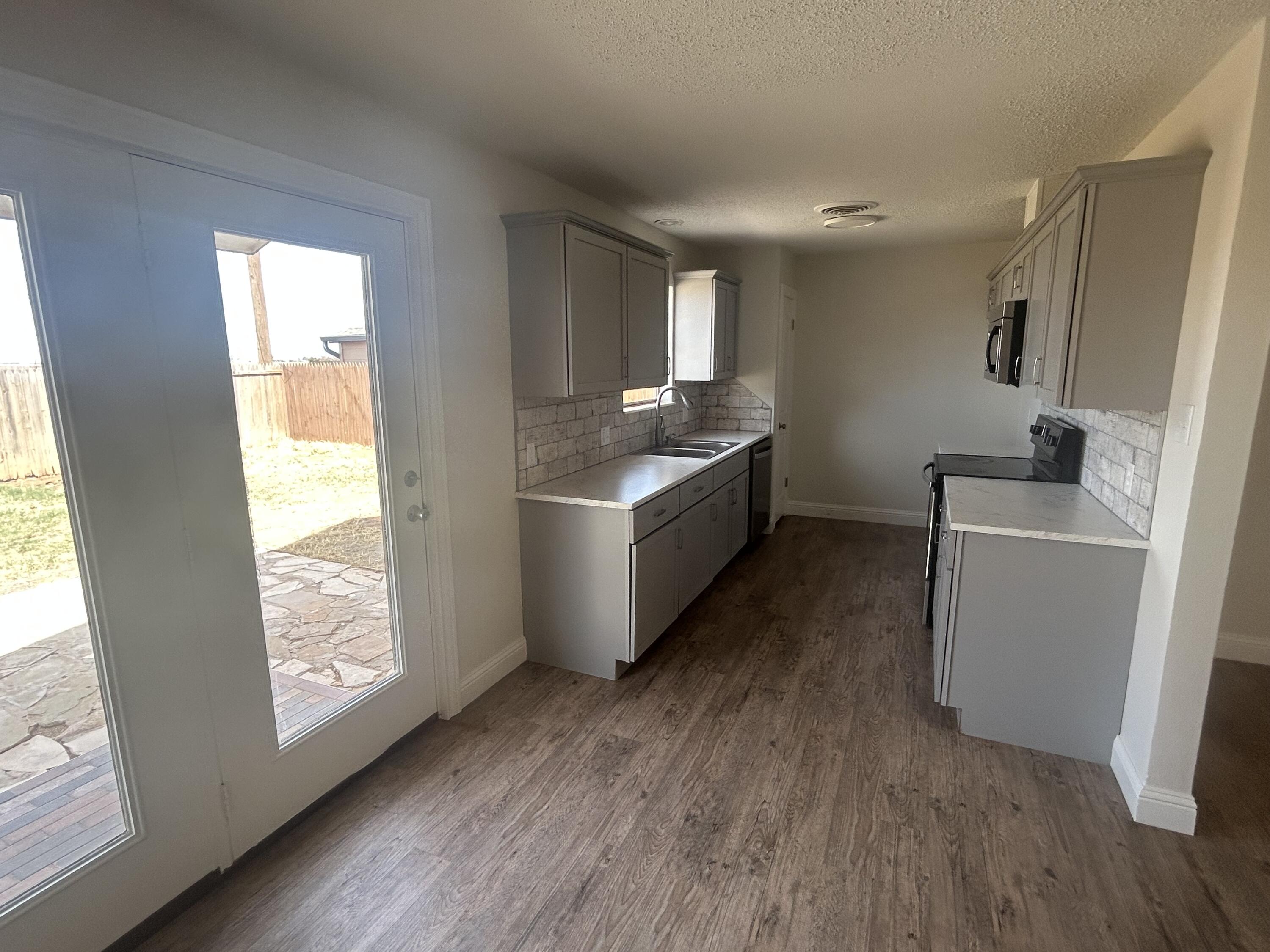 111 Bobby Street Levelland, TX 79336 - Photo 9 of 25 a kitchen with sink a refrigerator and wooden floor